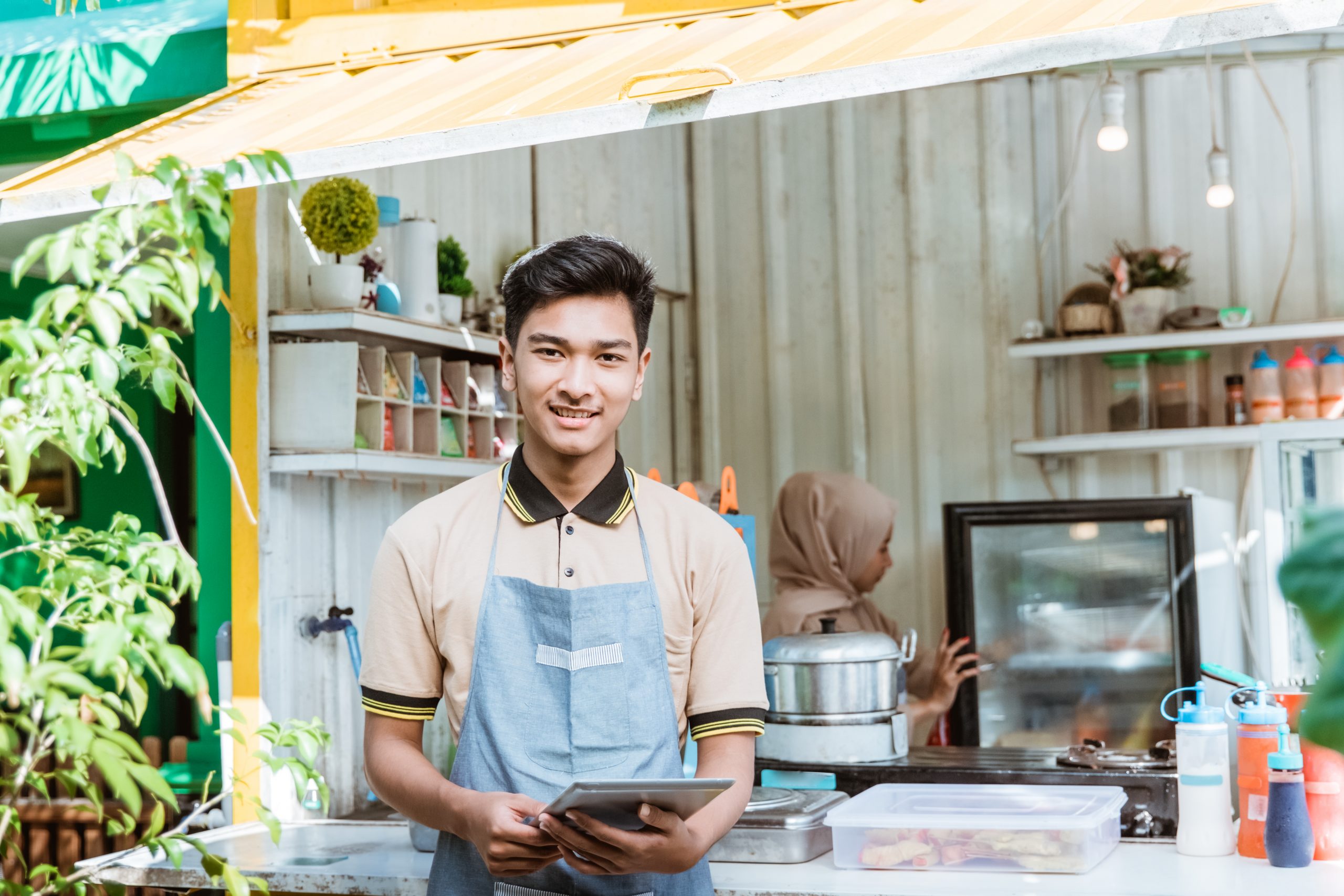 portrait of young muslim men selling food and drinks at his small shop made of truck container box